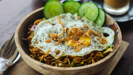 Fried egg with fried pasta in a wooden bowl. Balinese cuisine