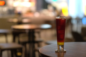 close up one glass of cocktail on wooden table at bar. colorful bokeh background