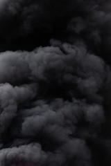 Background of black color clouds covered sky during strong fire. Dangerous and dramatic natural disaster