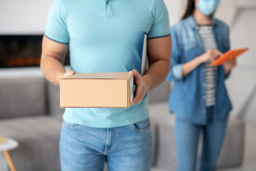 Man in light blue tshirt with box, woman with tablet.