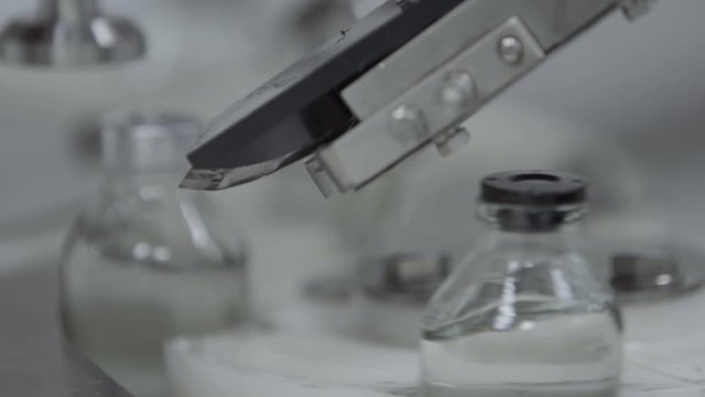 glass bottles filled and sealed with rubber caps on a medical solution conveyor line aluminium cap packaging section close up selective focus medical industry