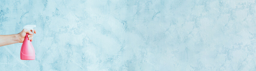 Domestic chores. Protection hygiene. Male hand with spray bottle for cleaning on blue textured wall.