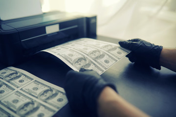 The concept of the global economic crisis. Illegal production of US dollars. Print money underground. Printing hundred dollar bills by a criminal.