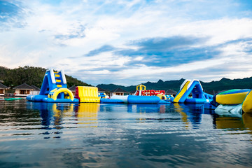 theme part floating in middle of the lake, obstacle course race, fun sport activity challenge with family holiday vacation trip, water activity sports inflated race course lake surrounded by mountains