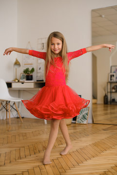  girl with long hair in red ball gown is dancing on quarantine of coronavirus at home in room