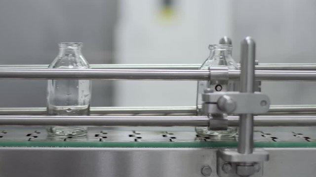 glass bottles on medical solution conveyor line close up medical industry