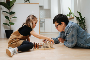 Dad and dau learning chess on a kitchen floor at home