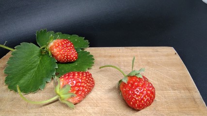 Fresh strawberries on a wooden table and black background