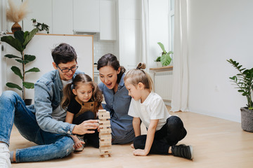 Family building tower from blocks, taking turns, picking and placing on top