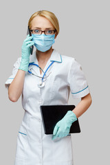 medical doctor nurse woman wearing protective mask and gloves - holding tablet pc and mobile phone