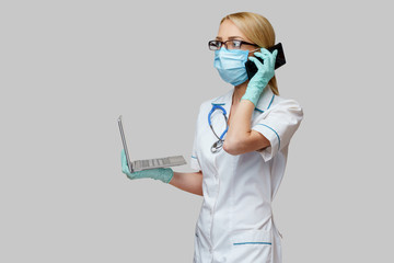 medical doctor nurse woman wearing protective mask and gloves - holding laptop and mobile phone