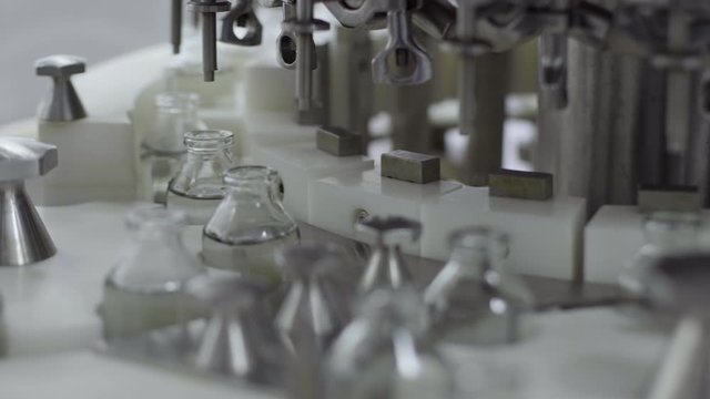 glass bottles on a medical solution conveyor at filling station close up selective focus medical industry