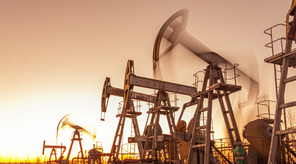 Oil pump rig. Oil and gas production. Oilfield site. Pump Jack are running. Drilling derricks for...