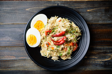 Northern Thai food (Tam Khanun), spicy pounded young jackfruit salad with boiled egg on wooden background, Top view