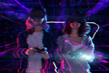 Closeup hands are holding wireless controllers joysticks. Boy and girl are playing in virtual reality game club. Friends in VR glasses are gaming. Entertainment and leisure concept. Modern technology.