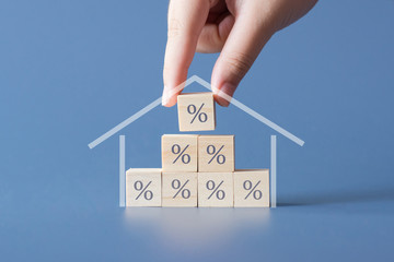 Hand building a house by wooden cubics with the percentage sign on them.Concept of Interest rate...