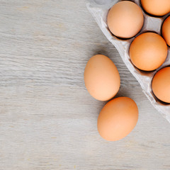 Close-up top view of organic raw eggs in egg box on rustic wooden background with copy space for your text, healthy eating concept.