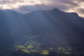 Fototapeta na wymiar Light rays shining down on beautiful green hills and houses in Tyrol, Austria. 