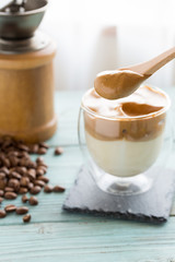 Whipped dalgona coffee with coffee beans scattered around- ダルゴナコーヒー