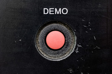 Red button demo old with scratches and dust, plastic, black background, retro.