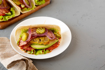Homemade Bacon Cheeseburger Taco on a white plate on a gray background, side view. Copy space.