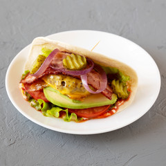 Homemade Bacon Cheeseburger Taco on a white plate on a gray surface, side view.