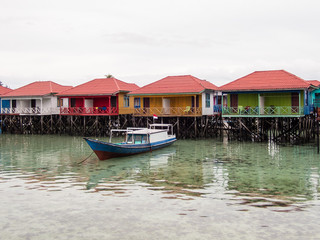 Naklejka na ściany i meble Colorful water cottages and boats at Derawan Island, North Kalimantan, Indonesia. Leisure and travel.
