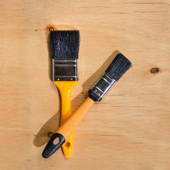 Two brushes with bristles against wooden plywood background with copy space. DIY time