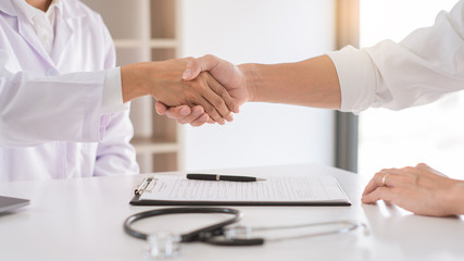 Attractive Doctor and patient shaking hands for encouragement and empathy, healthcare and assistance, Medical concept.
