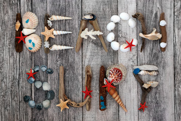 Abstract design of driftwood, seashells, blue cobalt sea glass & pebbles forming the word beach...