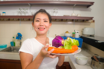 vegetable food and diet - home lifestyle portrait of young beautiful and happy Asian Japanese woman at domestic kitchen smiling cheerful in healthy nutrition and dieting concept