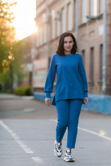 dark-haired girl walks around the city and posing in a blue suit