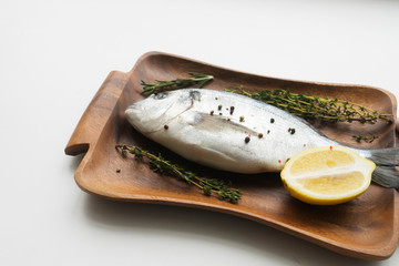 Raw fish cooking and ingredients. Dorado, lemon, herbs and spices. Top view on stone table