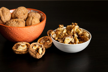 Handful of walnuts in orange ceramic bowl