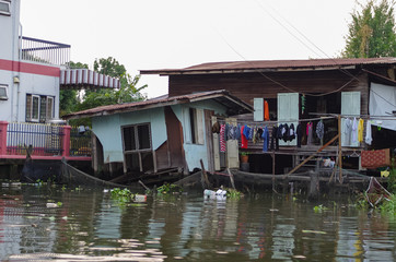 Fototapeta na wymiar Stilt houses at a klong in Bangkok. Klongs are the canals, that branch off from Chao Phraya river, the big river of Bangkok. The klong is the only way to get to these houses.