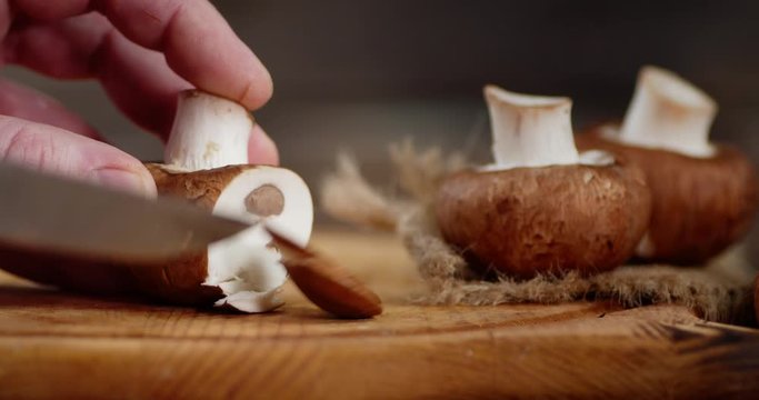 Male hands slicing fresh mushrooms on a wooden Board.