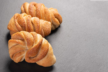 sweet, homemade brioche with cinnamon on dark background with copy space