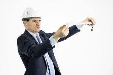 Serious architect in hard hat measures with tape measure on isolated white background. Construction, engineering tools, engineering and architecture concept