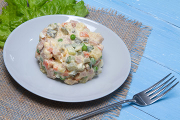 Olivier salad on a gray plate on a table in a restaurant, tasty and healthy dishes of various...