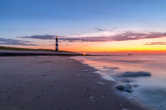 Lighthouse guiding the seamen throught the sunset on the gateway to the port