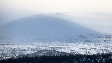 Winter landscape with foggy snowy mountains.