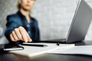 Woman freelancer sitting at table with laptop, focus on hand
