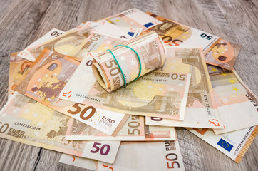 50 euros twisted into a roll on a background of euro banknotes. Business concept.