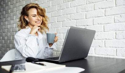 Smiling woman with curly hair sitting at table with laptop.