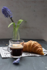 Special breakfast corner with a croissant and a coffee cup. A hyacinth vase is in the background.