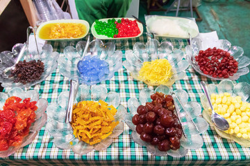 Different kinds of fruits and sweet dried fruits topping for ice cream and shaved ice.