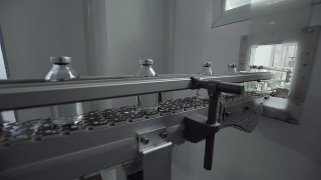 glass bottles filled and sealed with rubber and aluminum caps on medical solution conveyor line medical industry