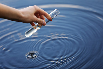 Water sample. Hand collects water to explore. Concept - water purity analysis, environment,...