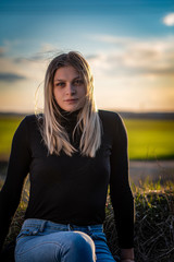 Portrait of a blonde in a black sweater at sunset. Photographed close-up.