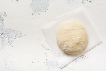 Dough and ingredients for the preparation of pasta, dough, eggs, flour, water and salt on a light rustic old table. Top view.